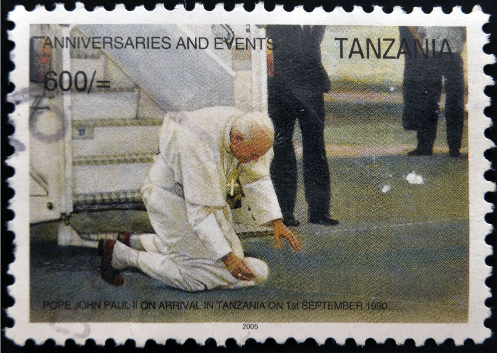 an image of Pope John Paul ii kissing the ground on a Tanzanian postage stamp